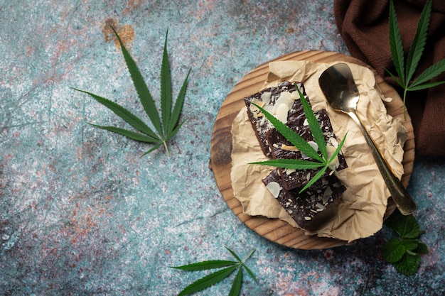 Foto gratuita brownies de cannabis y hojas de cannabis en tabla de cortar de madera