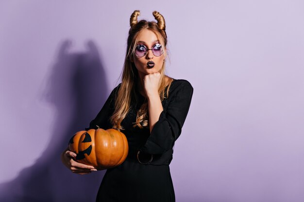 bruja con calabaza grande. Adorable chica rubia preparándose para halloween.