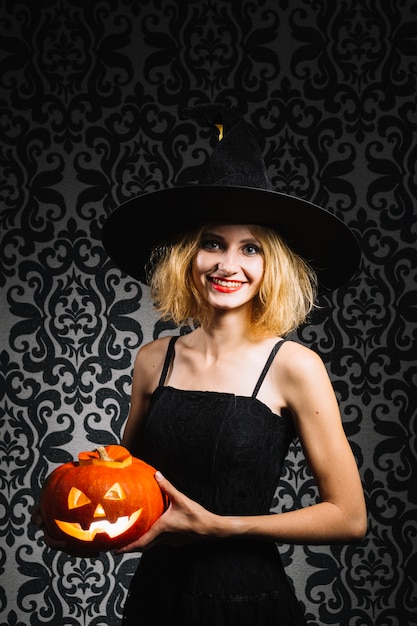 Foto gratuita bruja chica con calabaza sonriendo a la cámara