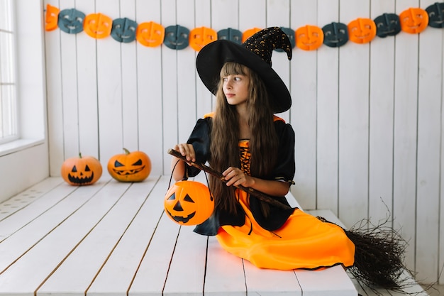 Bruja de Halloween joven con calabaza linterna y escoba