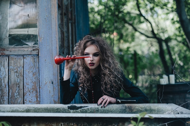 La bruja vintage realiza un ritual mágico, con elixir en la mano, en vísperas de Halloween.