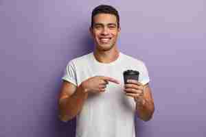 Foto gratuita brunet joven hombre vestido con camiseta blanca apuntando a una taza de café
