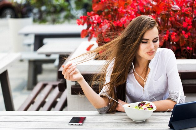 Brunette mujer mira algo en su tableta mientras está sentado en el restaurante