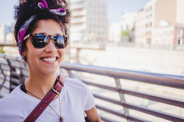 Foto gratuita brunette sonriente chica en gafas de sol de pie fuera