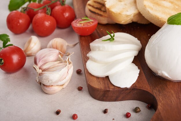 Bruschetta fresca con tomates, queso mozzarella y albahaca sobre una tabla para cortar. Aperitivo o refrigerio italiano tradicional, antipasto. Vista superior. Endecha plana. Chapata con tomate cherry.