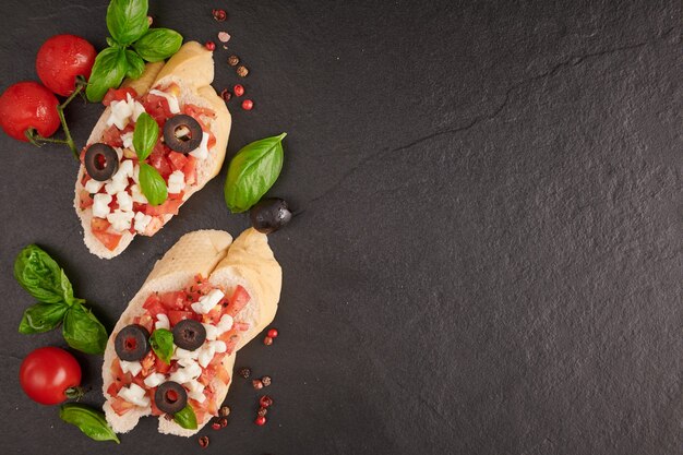 Bruschetta con tomates, queso mozzarella y albahaca sobre una tabla de cortar. Aperitivo o refrigerio italiano tradicional, antipasto. Bruschetta de ensalada caprese. Vista superior con espacio de copia. Endecha plana.