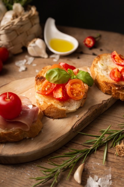 Bruschettas de alto ángulo con jamón y tomates en la tabla de cortar