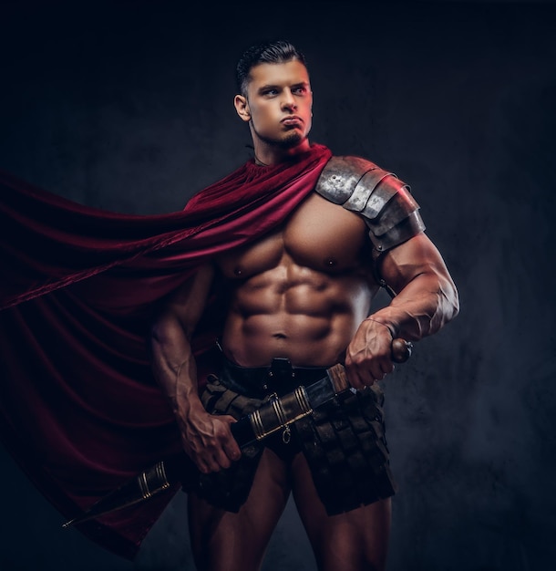 Brutal guerrero de la antigua Grecia con un cuerpo musculoso en uniformes de batalla posando sobre un fondo oscuro.