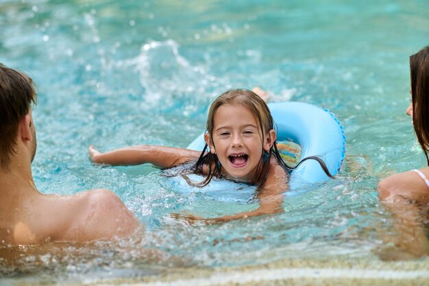 Buen tiempo. Linda chica y sus padres pasan tiempo en la piscina