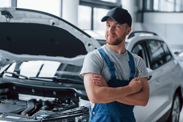 Buen trabajo. Empleado en el uniforme de color azul se encuentra en el salón del automóvil