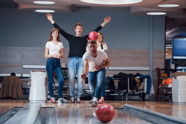 Buena suerte. Jóvenes amigos alegres se divierten en el club de bolos en sus fines de semana