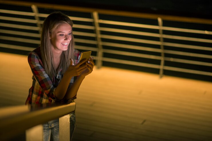 Buenas noticias. Hermosa niña comprueba algo en su teléfono inteligente y sonríe distraídamente.