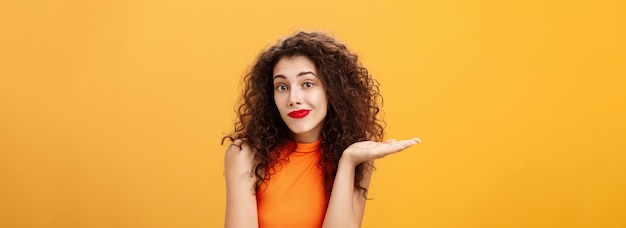 Foto gratuita bueno, lo siento, inconsciente y despistada, tonta mujer encantadora con peinado rizado, encogiéndose de hombros y sonriendo ingeniosamente.