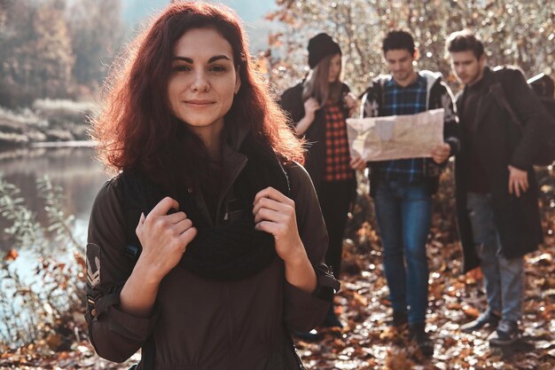 Los buenos amigos se divierten en el bosque de otoño, usan un mapa para encontrar el mejor lugar para caminar.