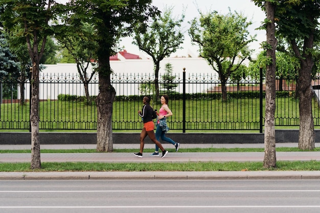 Foto gratuita buenos amigos en ropa deportiva corriendo en la ciudad hablando de mujeres multiétnicas haciendo ejercicio físico