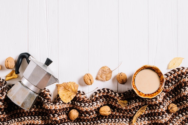 Bufanda y hojas cerca de café y nueces