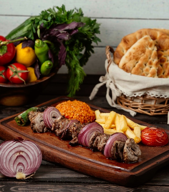 Bulgur carne cebolla y papas fritas en una mesa de madera