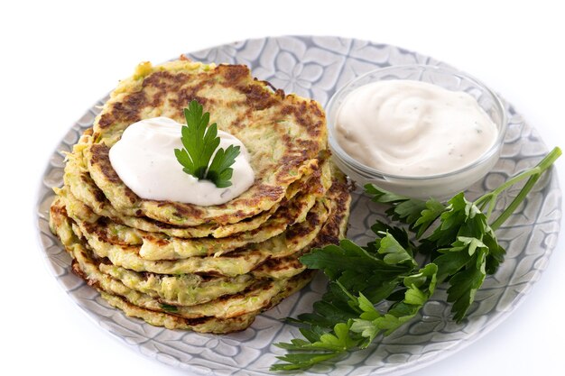 Buñuelos de calabacín con salsa de yogur aislado sobre fondo blanco.