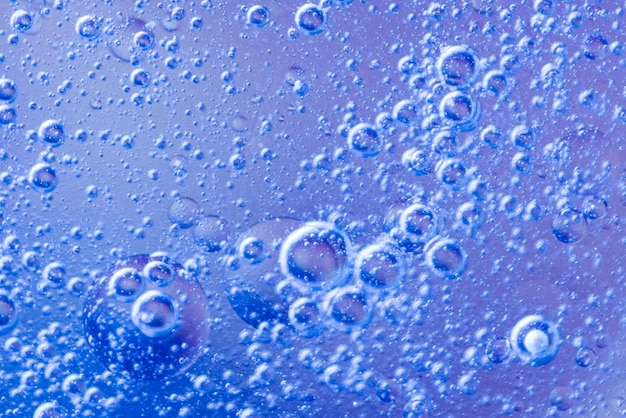 Burbujas de aire abstractas en líquido sobre fondo azul desenfocado