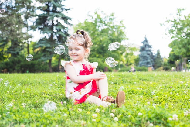 Burbujas sobre la niña sentada en el parque