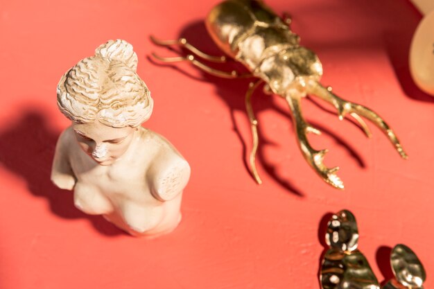 Busto de Venus junto a escarabajo dorado.