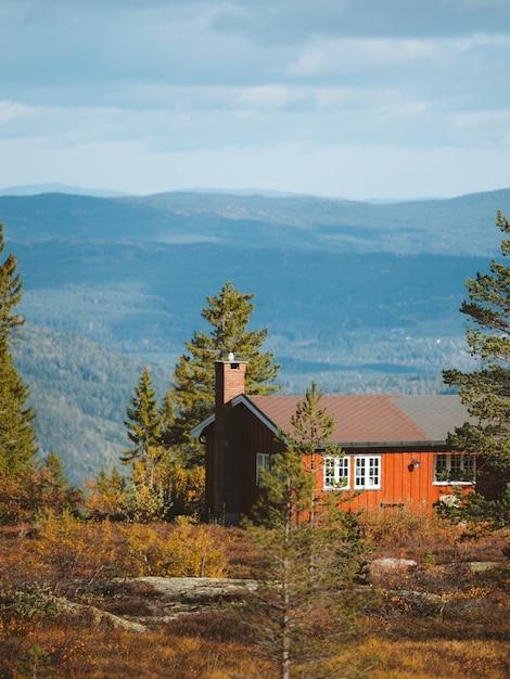 Una cabaña de madera en un bosque con hermosas montañas rocosas en el fondo en Noruega