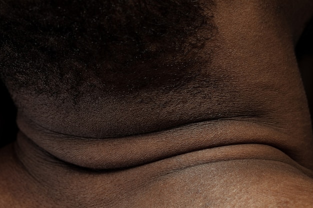 Cabeza, cuello. Textura detallada de la piel humana. Primer plano del cuerpo masculino joven afroamericano. Concepto de cuidado de la piel, cuidado corporal, salud, higiene y medicina. Se ve bella y bien cuidada. Dermatología.