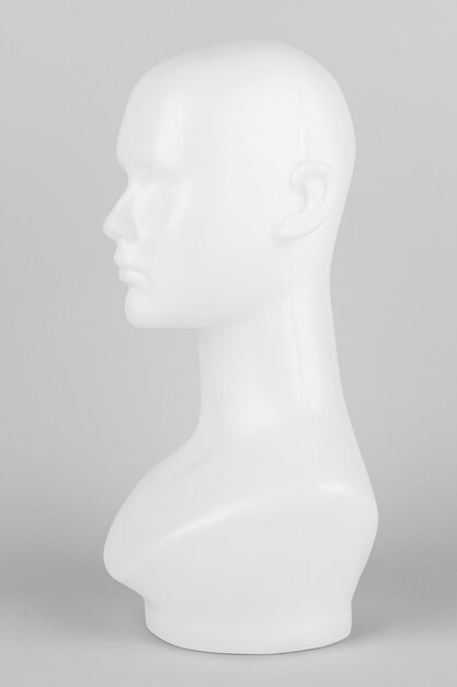 Cabeza de maniquí blanco de perfil sobre un fondo gris