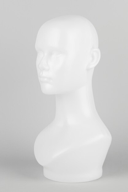 Cabeza de maniquí blanco de perfil sobre un fondo gris