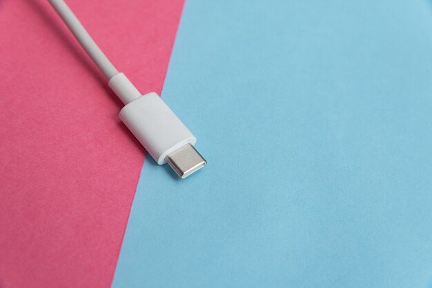 Cable USB tipo C sobre fondo rosa y azul