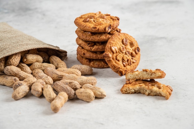 Cacahuetes orgánicos crudos y deliciosas galletas en la mesa de mármol.