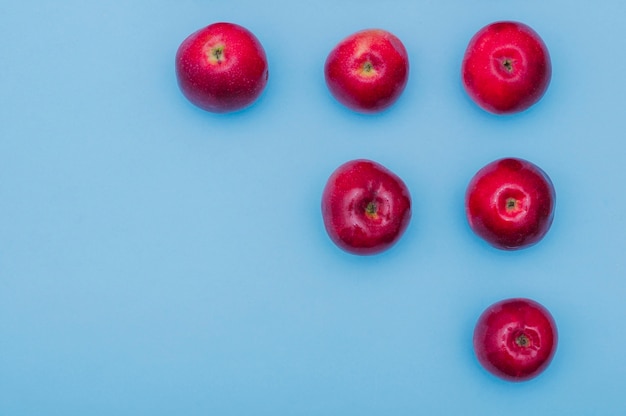 Cada vez más fila de manzanas rojas frescas sobre fondo azul