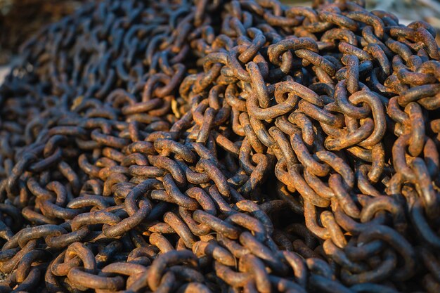 La cadena de ancla oxidada se vierte en el enfoque selectivo del primer plano del muelle Montón de vieja idea de eslabones de cadena oxidada pesada para el fondo