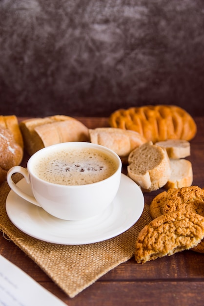 Café alto ángulo rodeado de galletas.