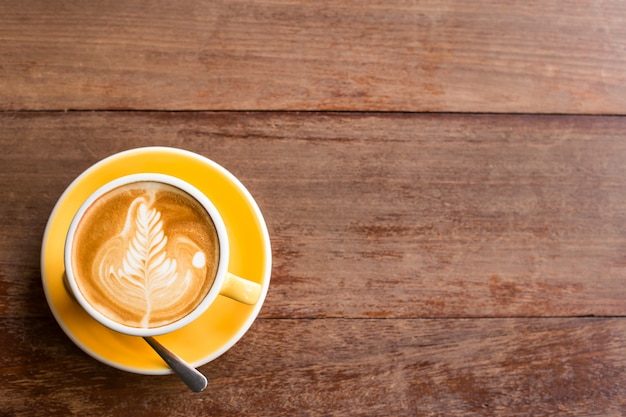 Café caliente de Latte del arte en una taza en el vector de madera.