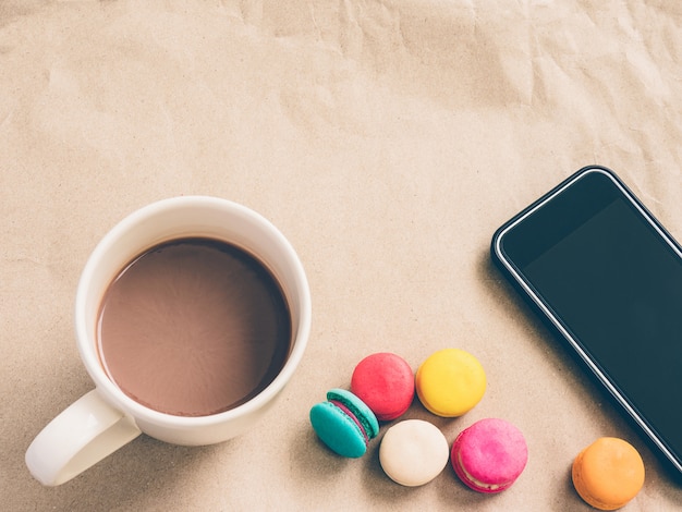 Café caliente, macarrones de colores y smartphone.