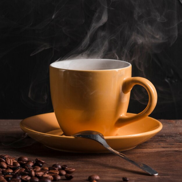 Café caliente en taza con cuchara en plato