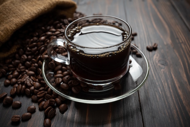 Café caliente en un vaso sobre la mesa de madera.