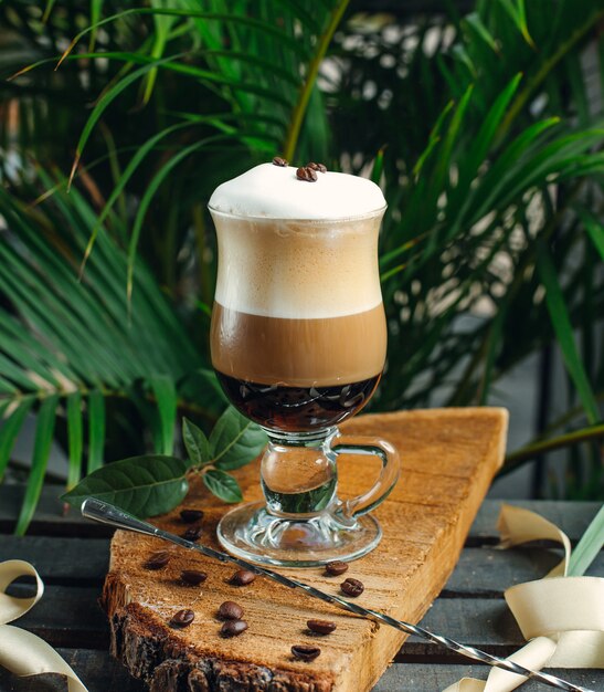 café en capas con crema y granos de café sobre tabla de madera rústica