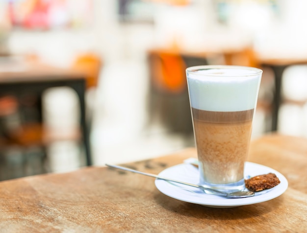 Café capuchino en un vaso transparente sobre mesa