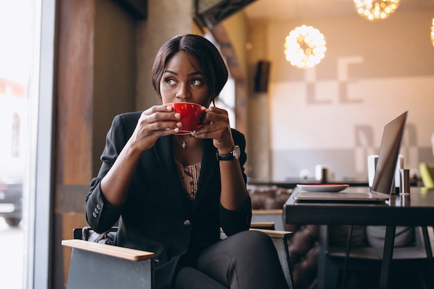 Café de consumición afroamericano de la mujer de negocios en una barra