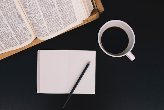 Café y cuaderno cerca del libro