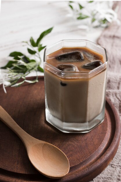 Café con cubitos de hielo en vaso y cuchara de madera