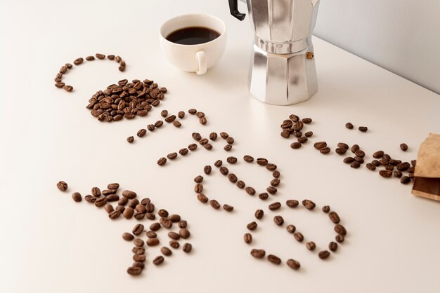Café escrito con granos de café en la mesa blanca