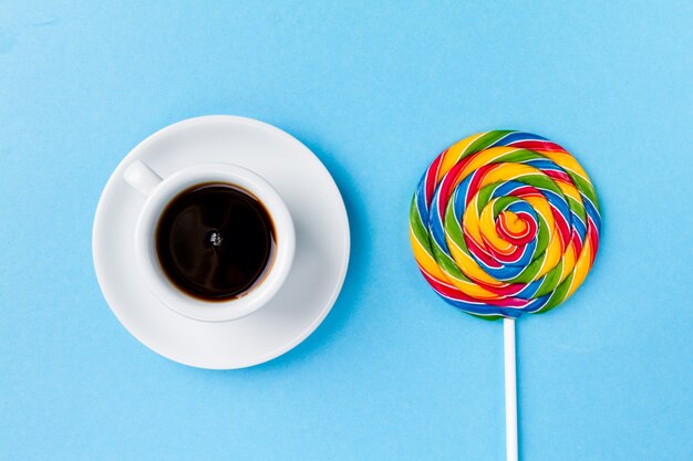 Café expreso de café de la taza con Candy Lollypop Desayuno en fondo de mesa azul brillante