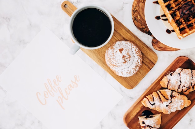 Café, por favor envíe un mensaje de texto en papel con un desayuno saludable y una taza de café sobre el fondo de mármol