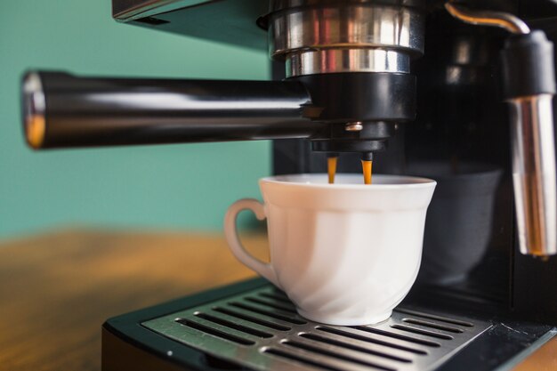 Café fresco vertiendo en taza de cerámica