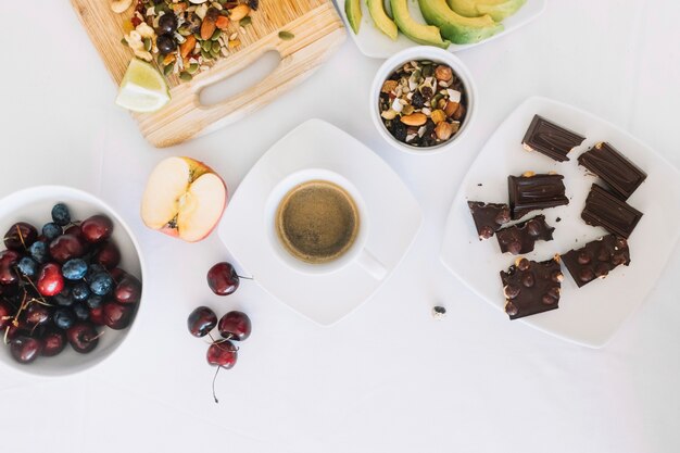 Café; fruta seca; trozos de chocolate; Cereza y frutas sobre fondo blanco