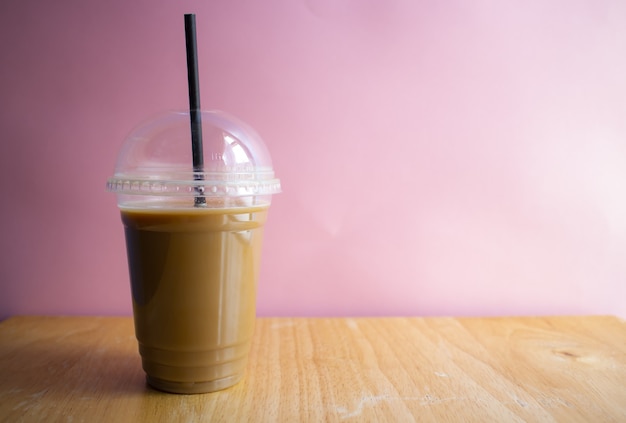 Café helado sobre una superficie de madera con una pared rosa