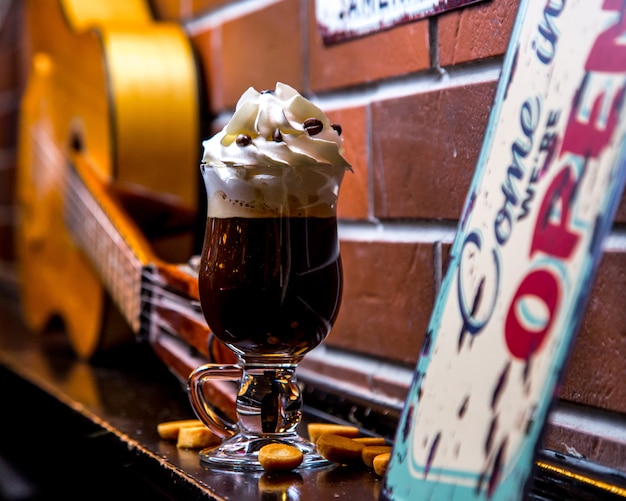 Foto gratuita café irlandés con crema batida decorado con chispas de chocolate en la pared de ladrillo